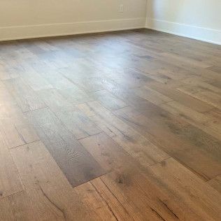 Wood-plank flooring in a room with white baseboards and walls. Natural light illuminates the surface.
