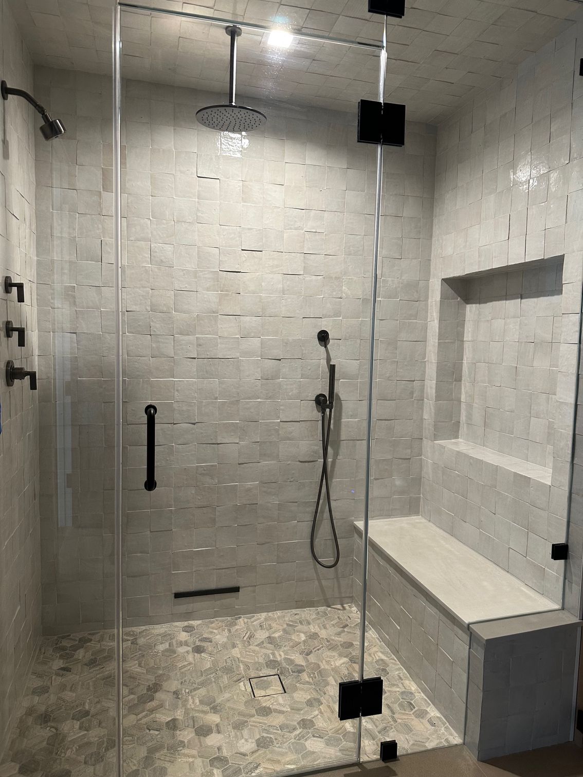 Modern office hallway with glass walls, black trim, and a view of a waiting area.