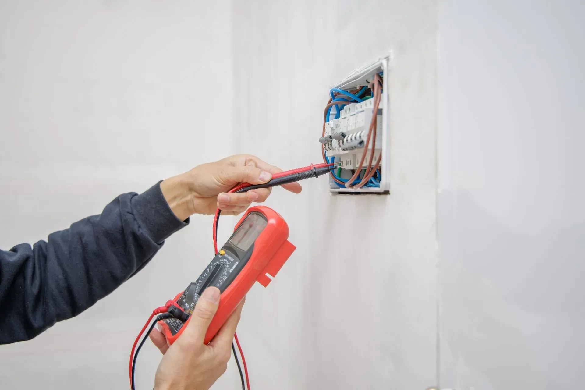 Electrician Is Using a Screwdriver to Install the Electric Power. Electrician Services in Northville MI