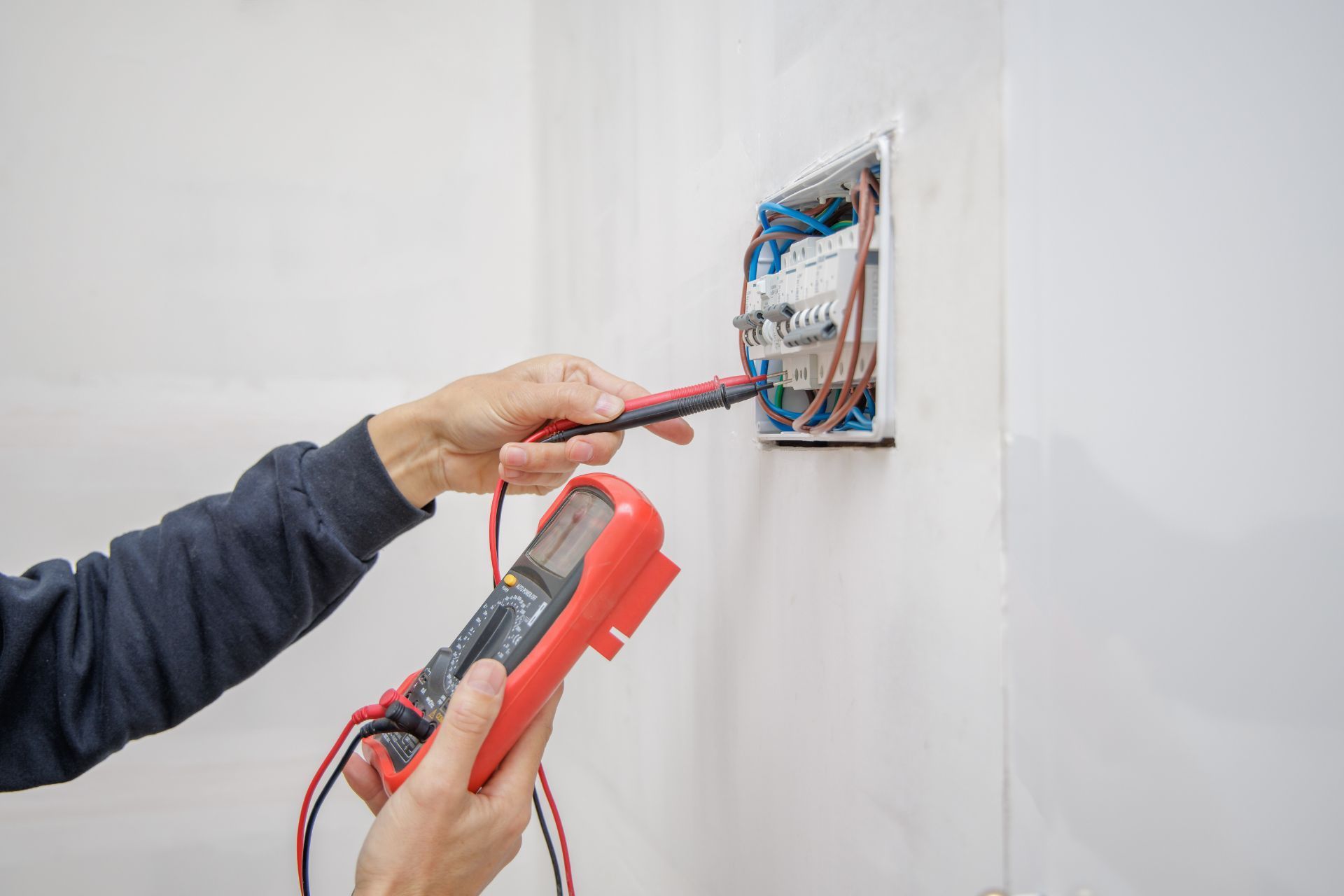 Electrician Is Using a Screwdriver to Install the Electric Power. Electrician Services in Northville MI