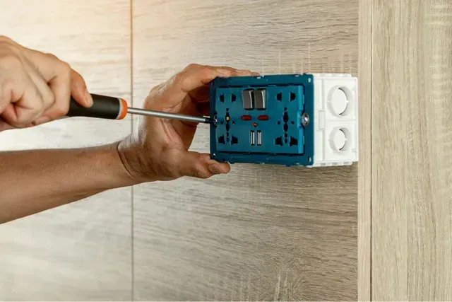 Electrician Is Using a Screwdriver to Install the Electric Power. Electrician Services in Livonia MI