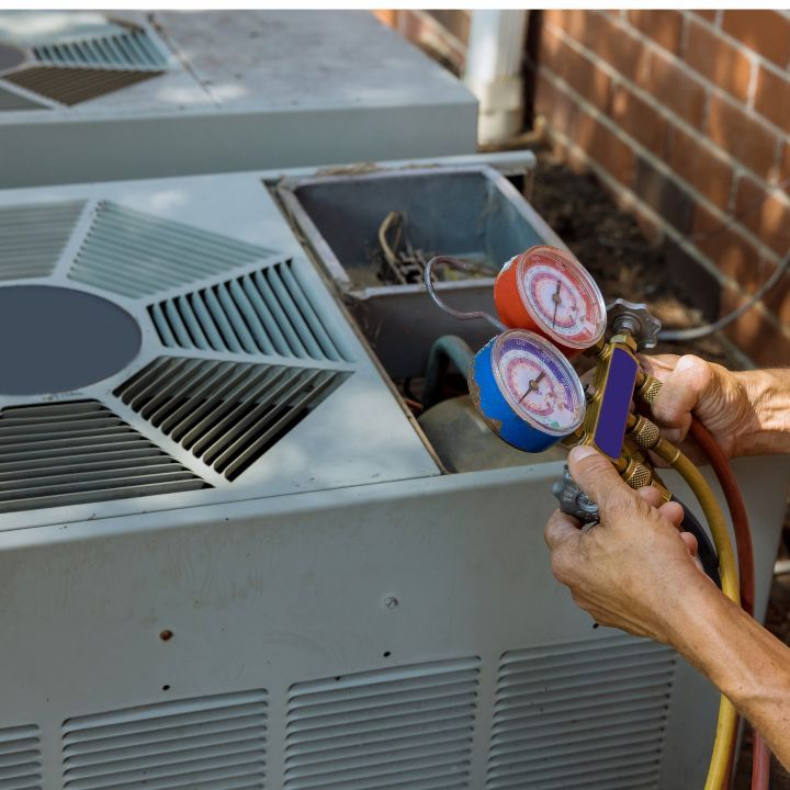 Hands attaching gauges to an AC unit for servicing, outdoors.
