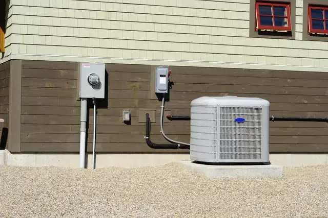 Four outdoor air conditioning units on a gravel bed near a building's exterior.