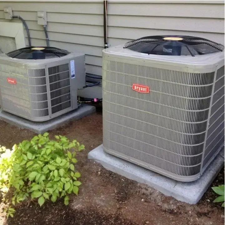 Two Bryant air conditioning units on concrete pads next to a building.