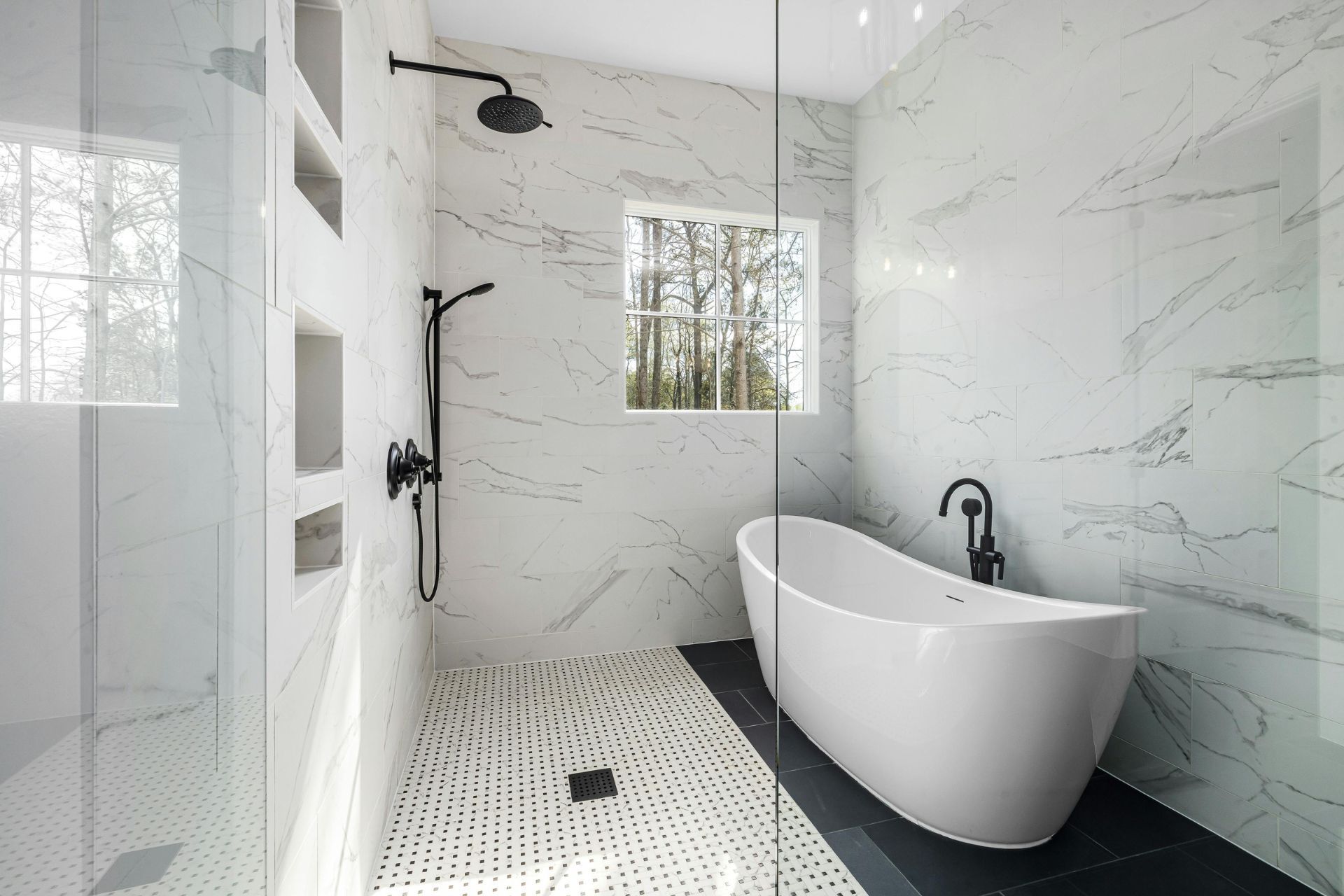 Modern bathroom with white marble tile, black fixtures, freestanding tub, and a small window. Plumbing Services in Livonia