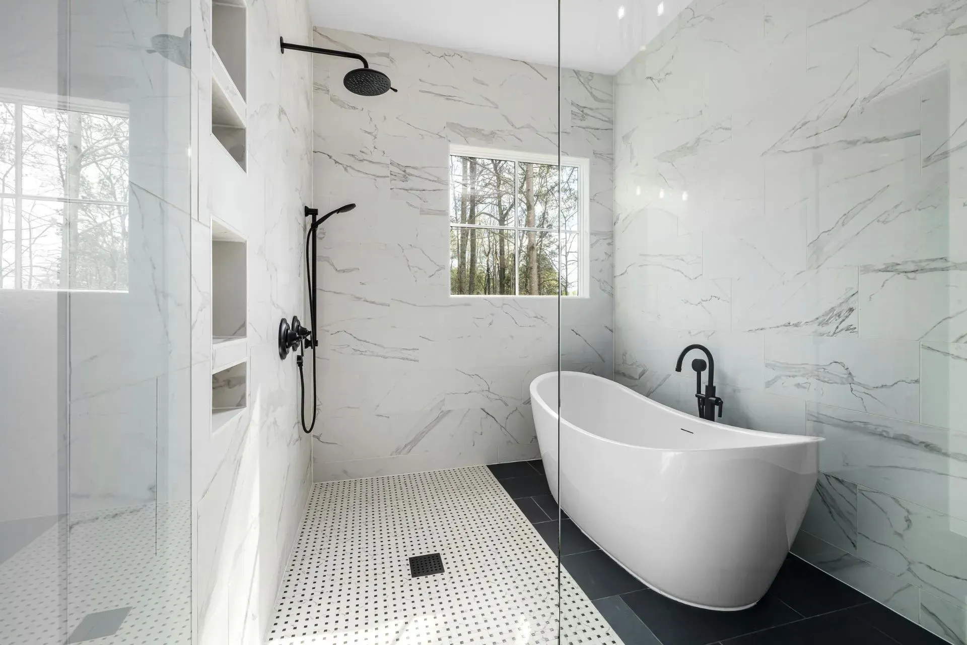 Modern bathroom with white marble tile, black fixtures, freestanding tub, and a small window. Plumbing Services in Livonia