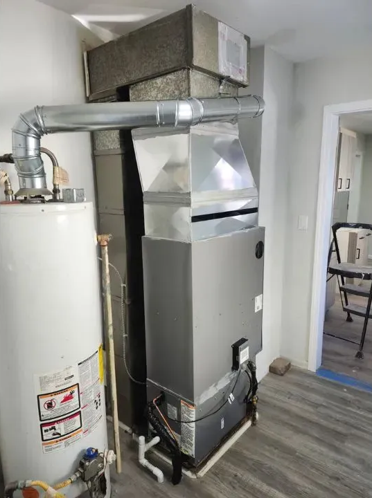 HVAC furnace and water heater in a utility closet with silver ductwork and white walls