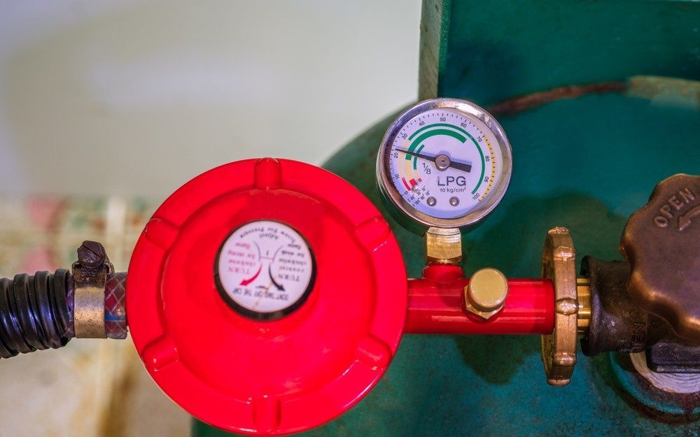 Red LPG Gas Regulator and Gauge Attached to a Green Tank — Rob Powell Plumbing Pty Ltd in Lismore, NSW