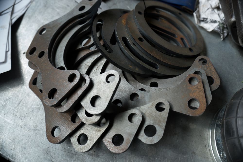 Piles of Cut Metal Parts, Possibly for Machinery, With Multiple Holes — Rob Powell Plumbing Pty Ltd in Coraki, NSW