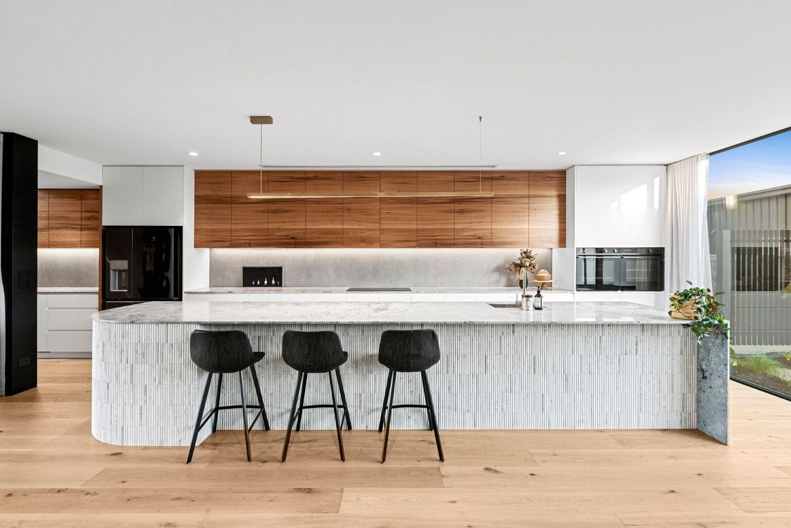 A kitchen with a large island and three stools.