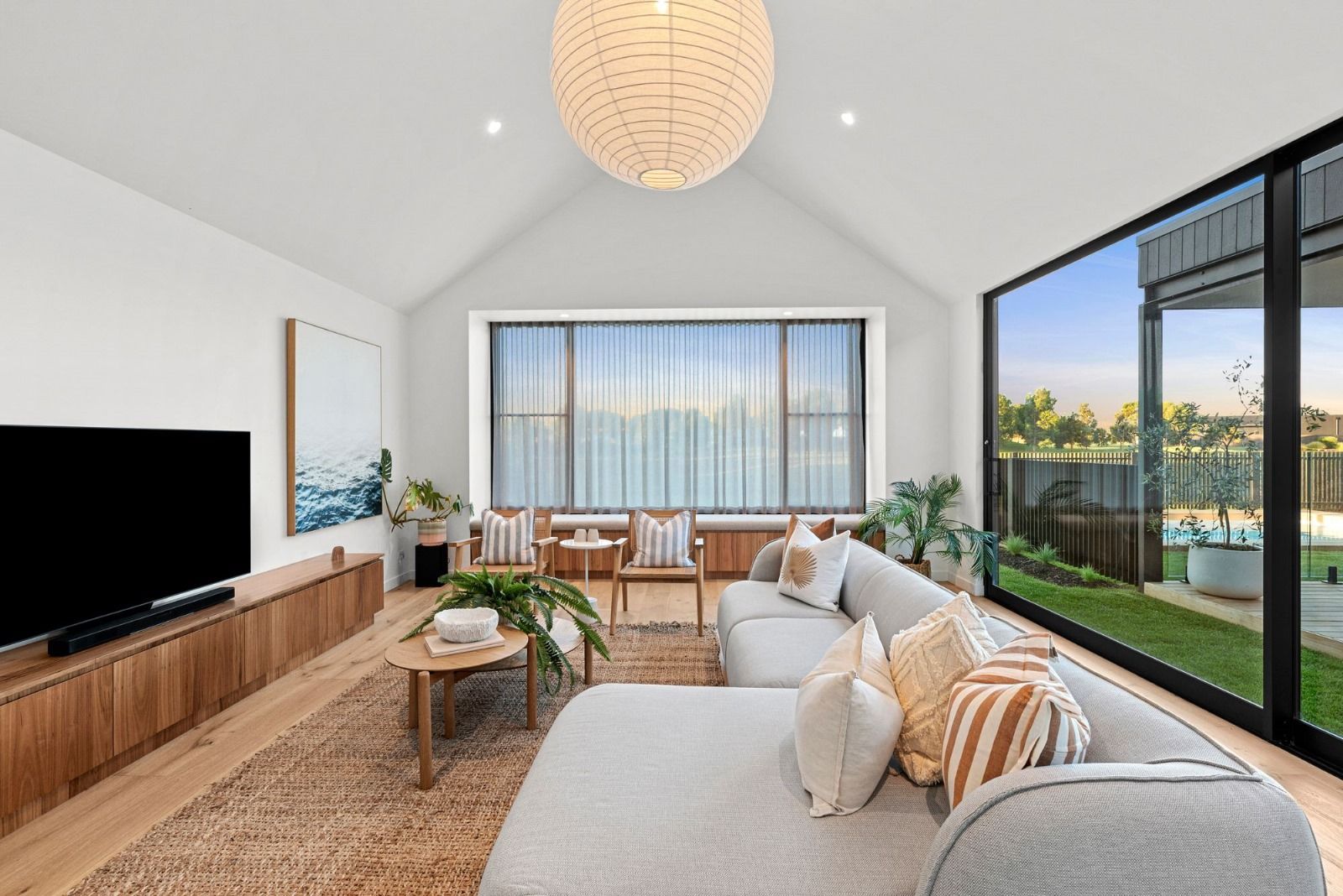 A living room with a couch , television , and large windows.