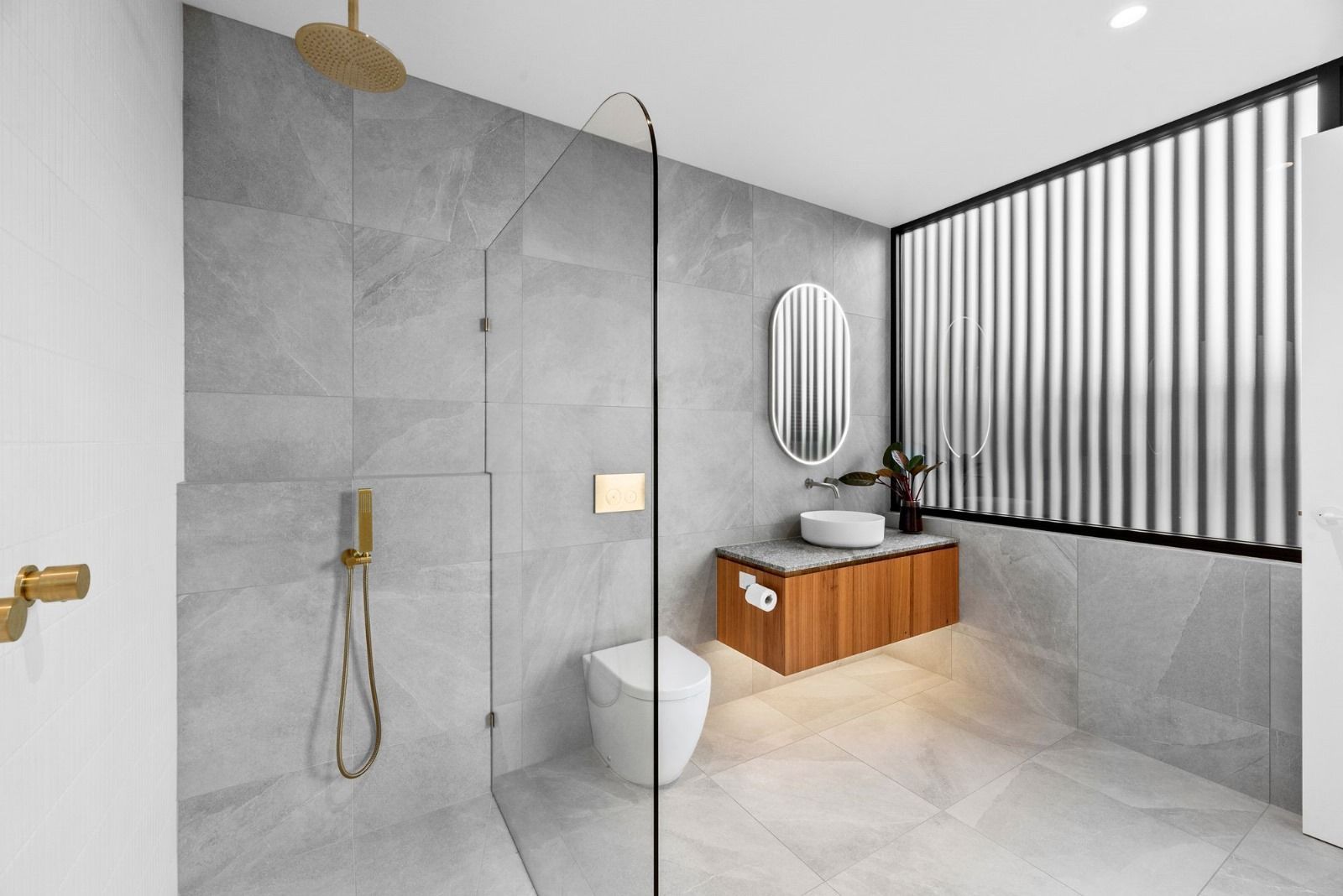 A bathroom with a walk in shower , toilet , sink and mirror.