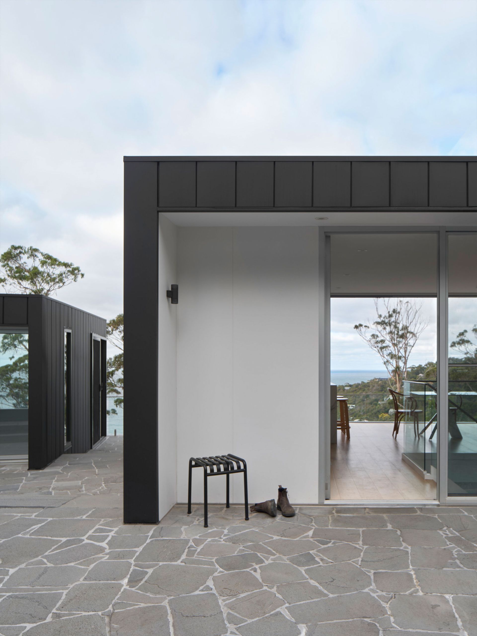 A white building with a black roof and a stool in front of it