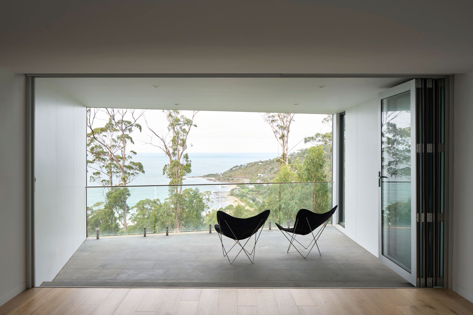 Two chairs are sitting on a balcony overlooking the ocean.