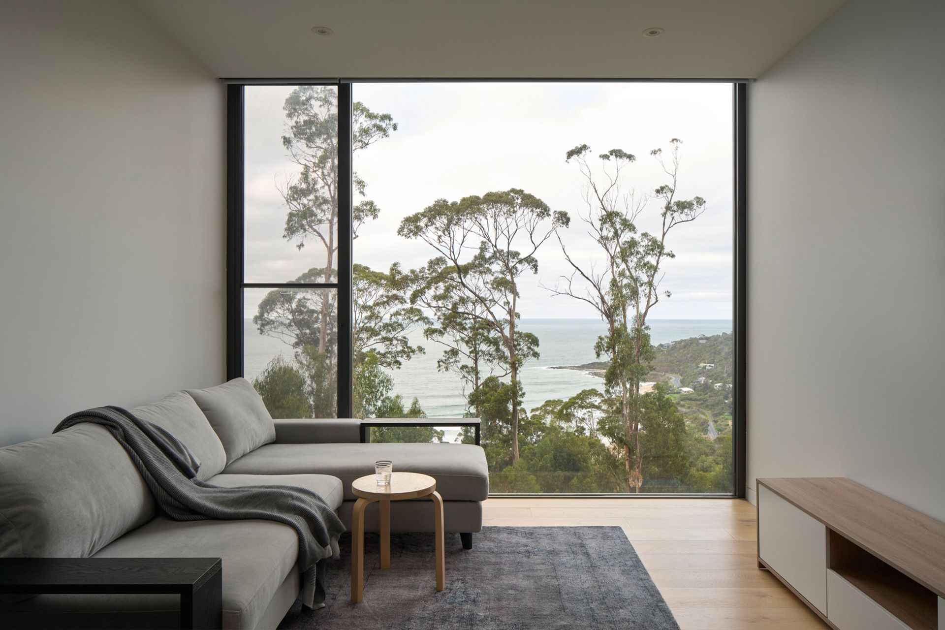 A living room with a couch and a large window with a view of the ocean.