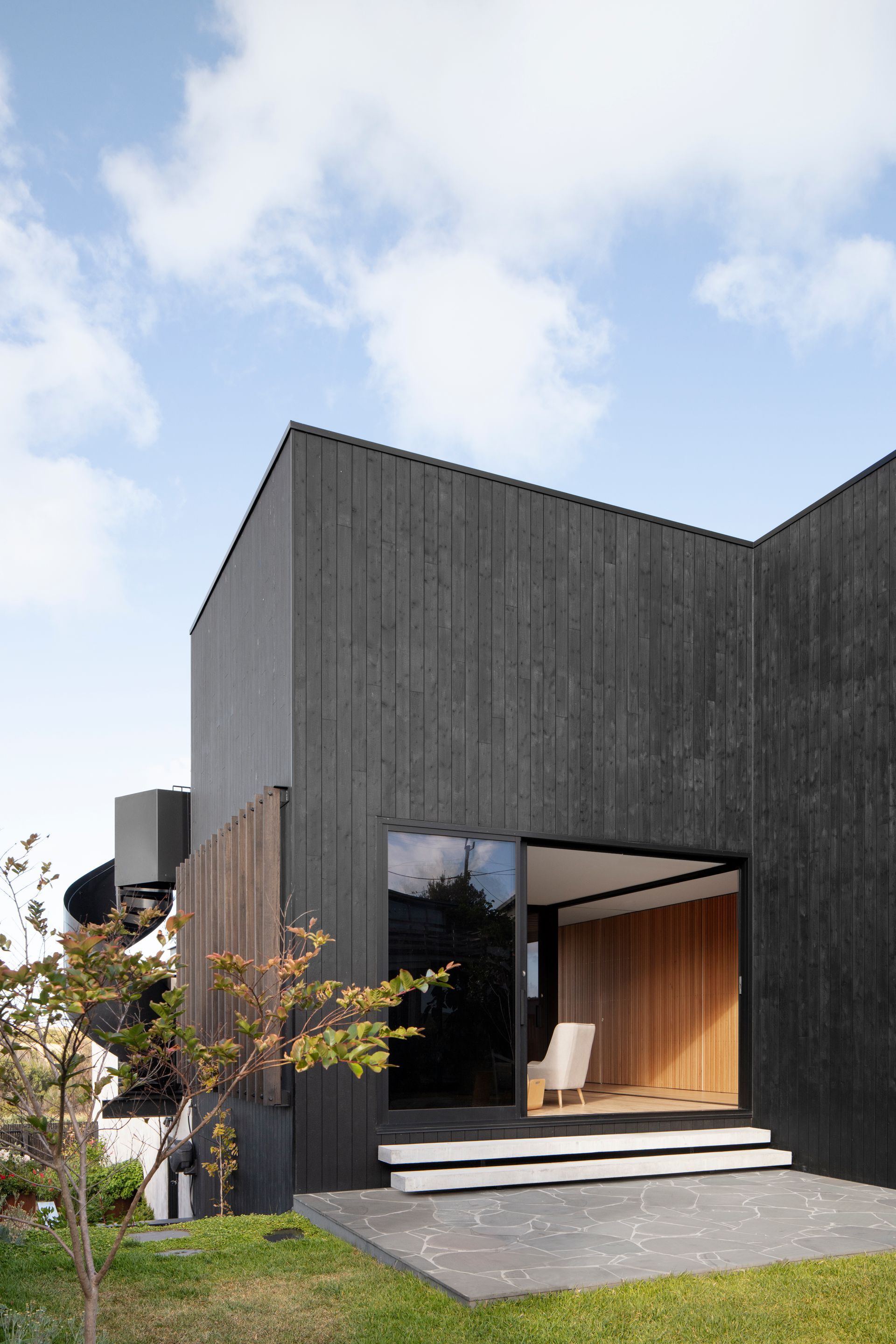 A black house with a large window and stairs leading to it.