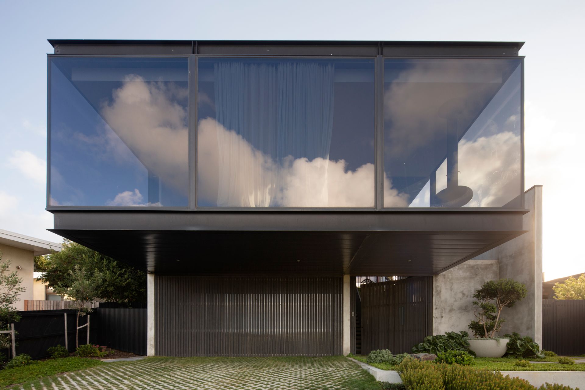 A modern house with a lot of windows and a reflection of clouds in the windows.