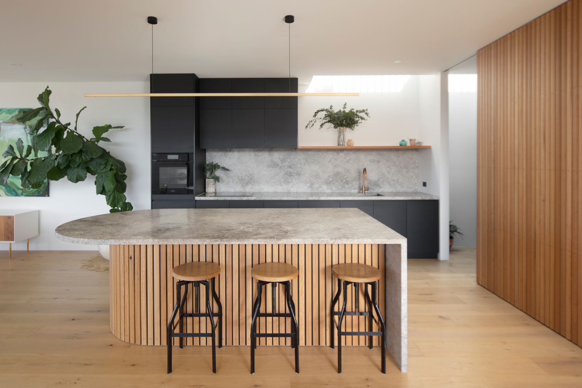 A kitchen with a large island and three stools.