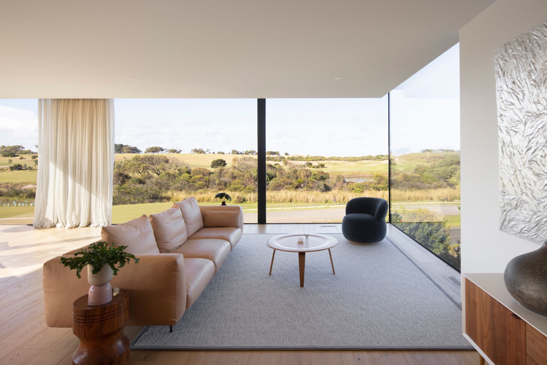 A living room with a couch , table and chairs and a view of a field.