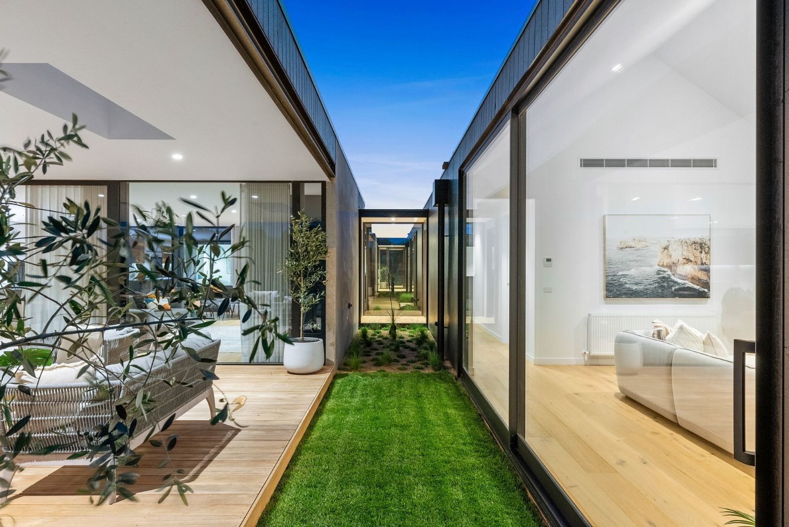 A house with a lot of windows and a lush green lawn.