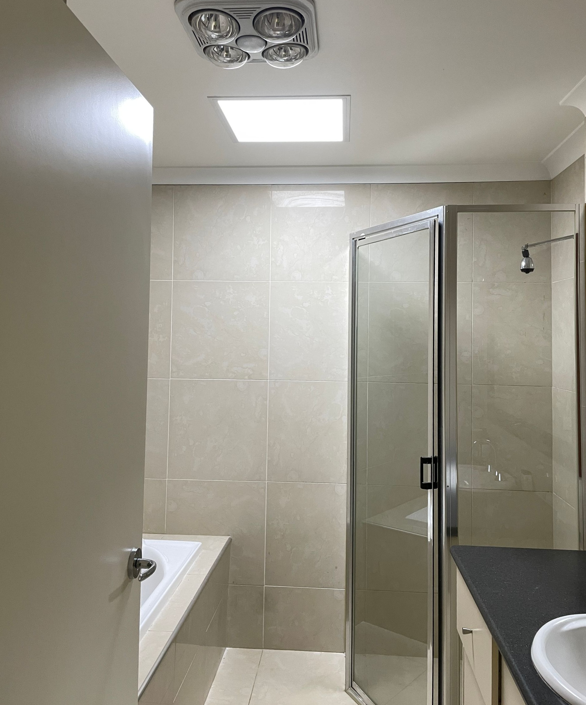 Bathroom interior with shower, vanity, and ceiling fan/light combo — All Top Roofing In Royalla, NSW