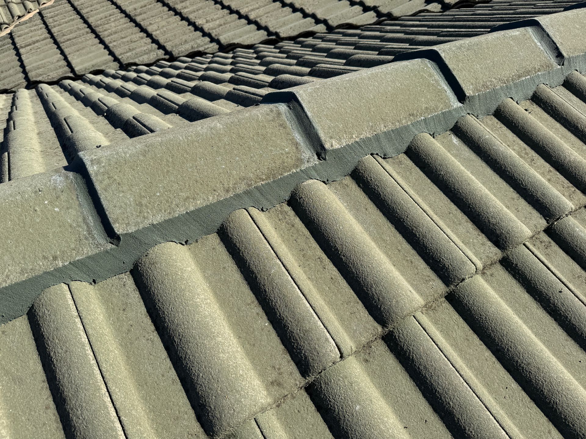 Close-up view of a textured, gray roof with interlocking tiles and a ridge cap — All Top Roofing In Tuggeranong, ACT