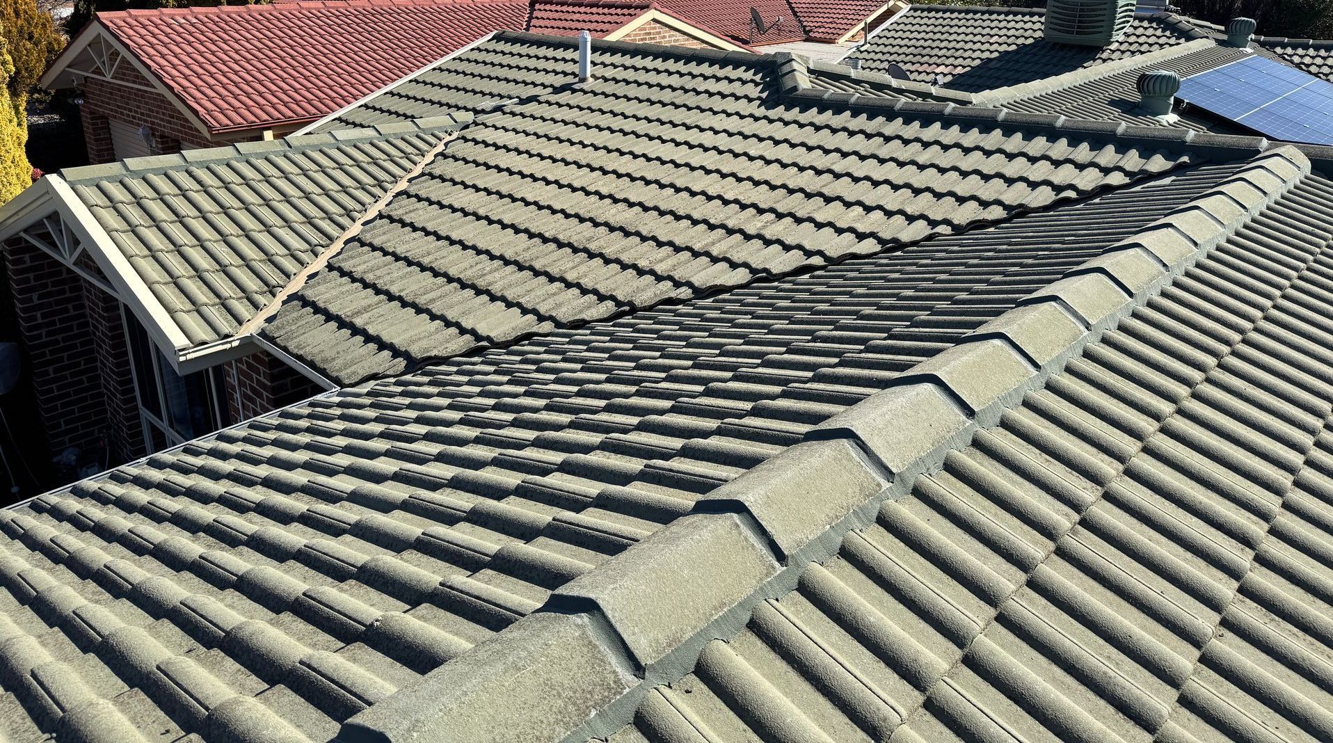 Close-up of a gray tile roof, with a red-tiled roof in the background — All Top Roofing In Woden, ACT