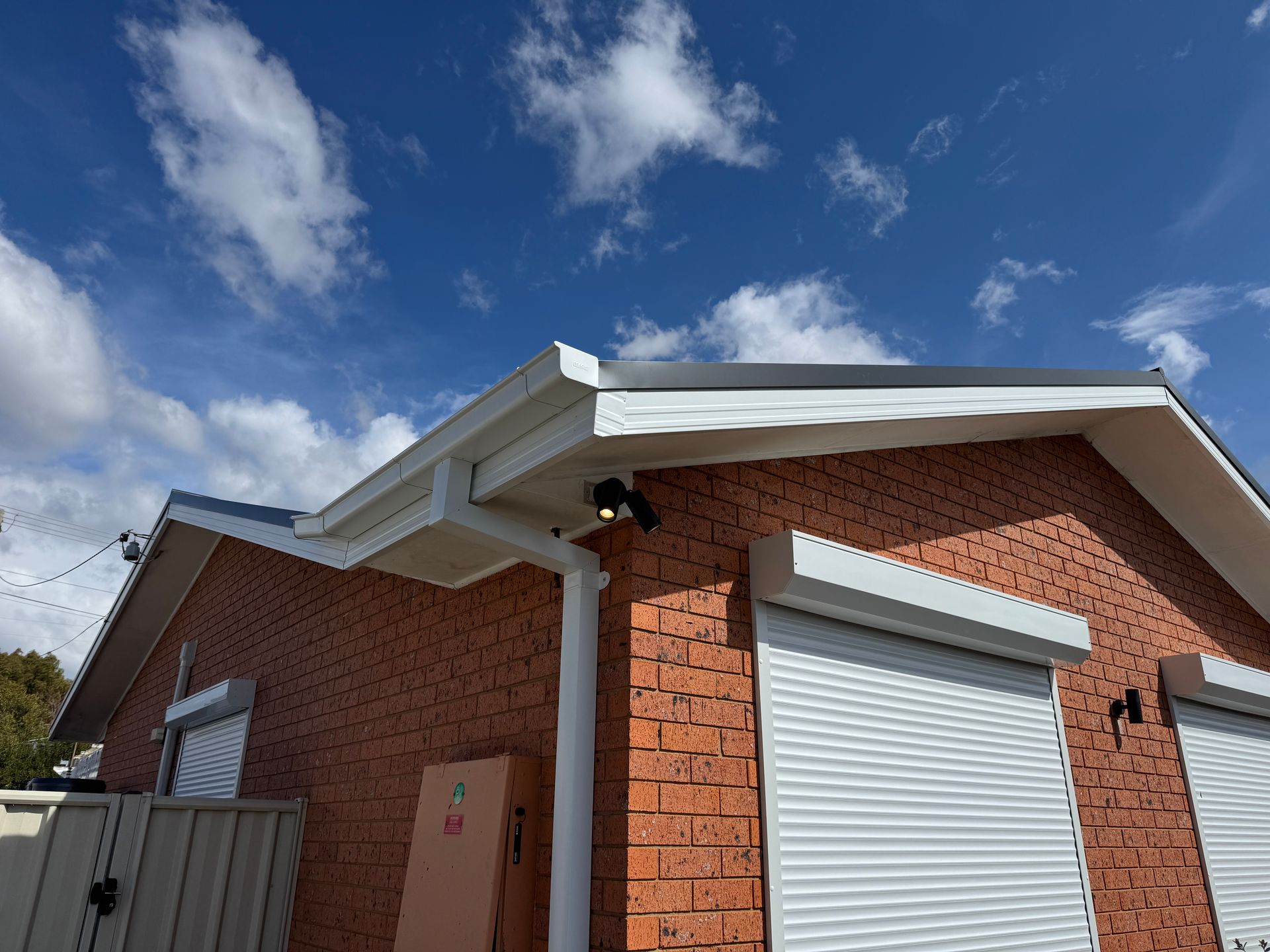 white gutters on a house roof, with a blue sky backdrop — All Top Roofing In Royalla, NSW