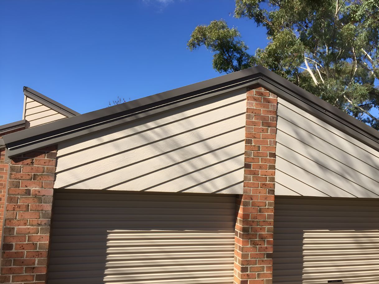 A Brick Building With A Garage Door And A Roof — All Top Roofing In Royalla, NSW