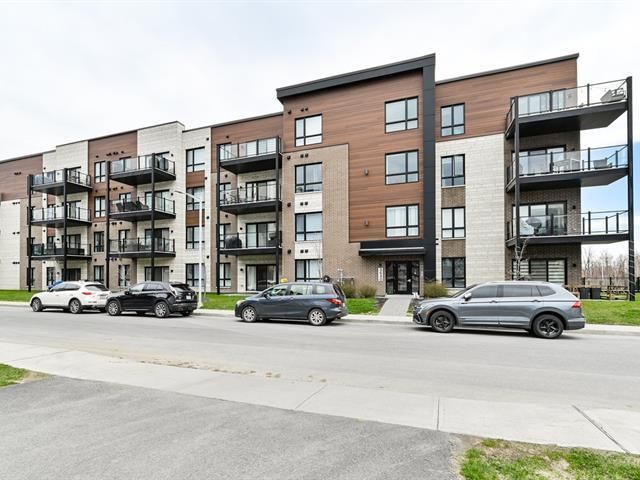 Un grand immeuble avec des voitures garées devant.