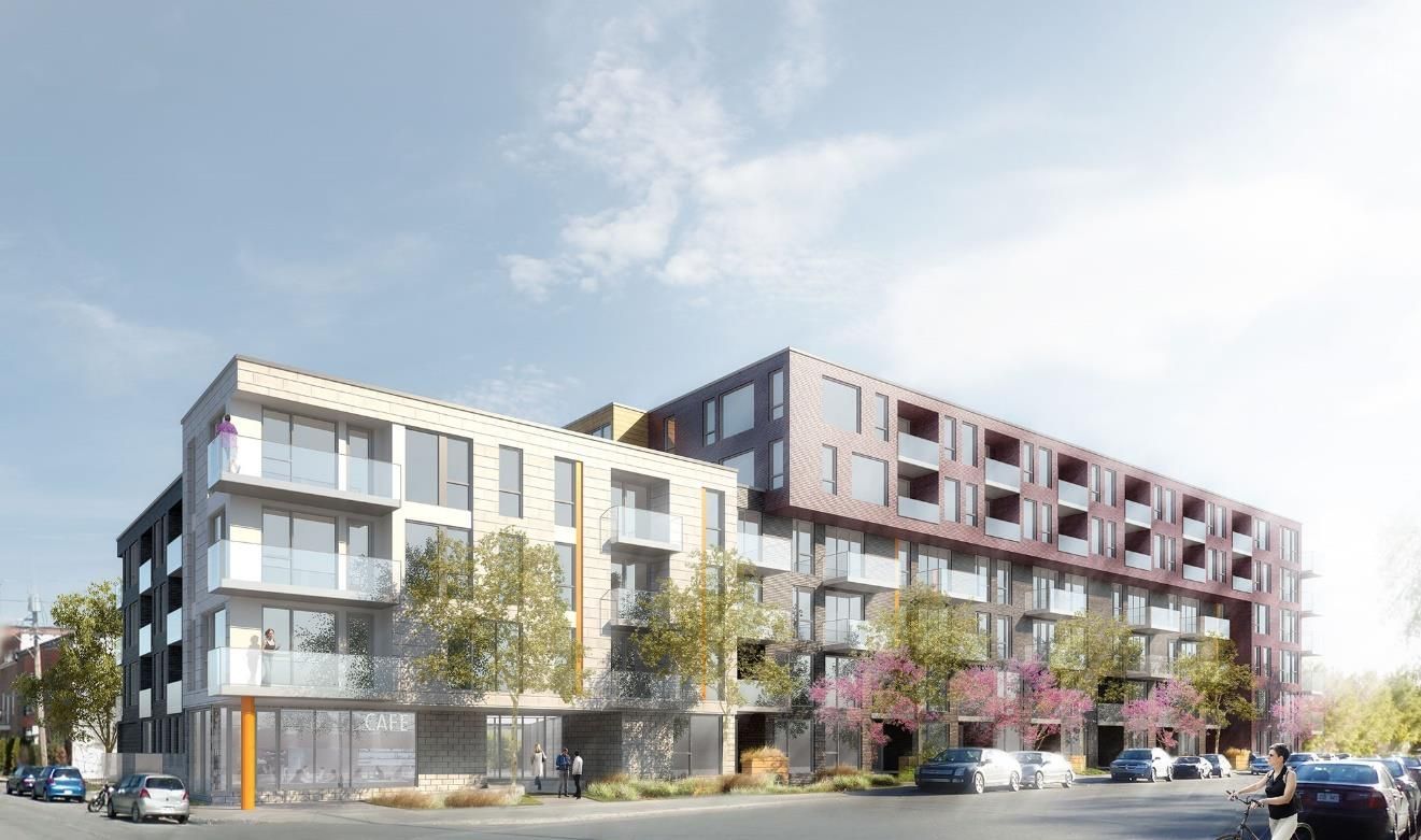 Un grand bâtiment avec de nombreuses fenêtres se trouve au coin d'une rue.