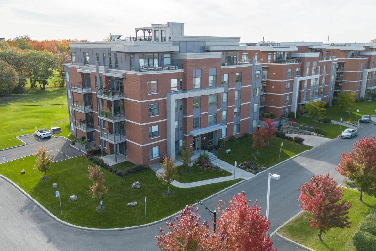 Une vue aérienne d'un grand immeuble avec des voitures garées devant lui.