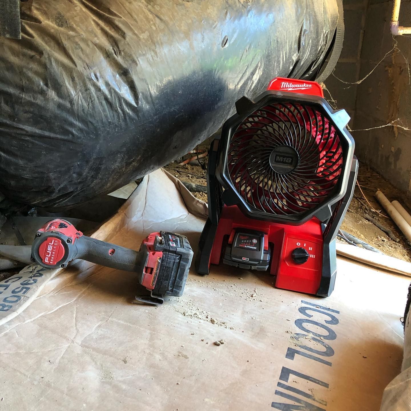 A red and black fan is sitting on top of a cardboard box.