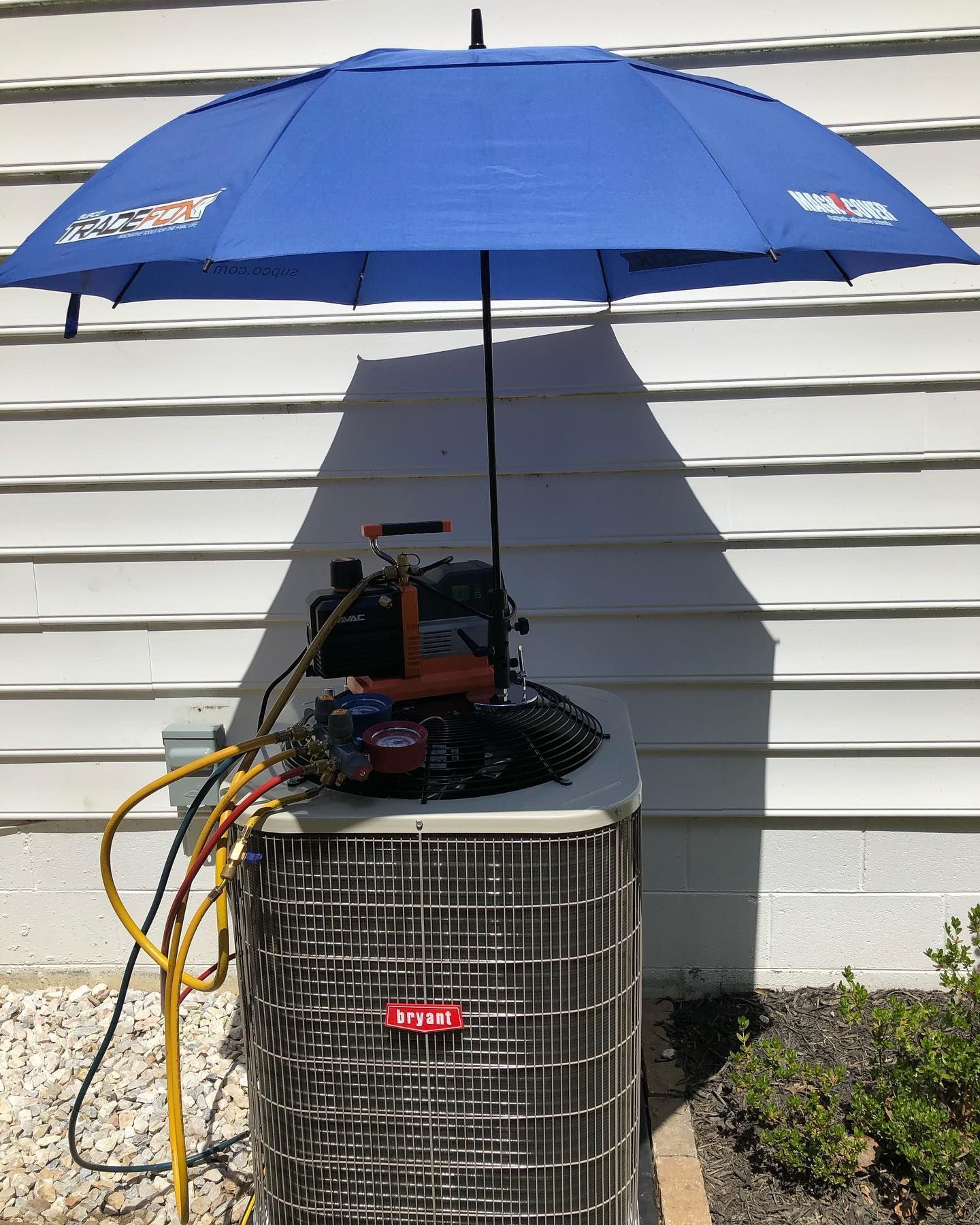 A blue umbrella is sitting on top of an air conditioner.