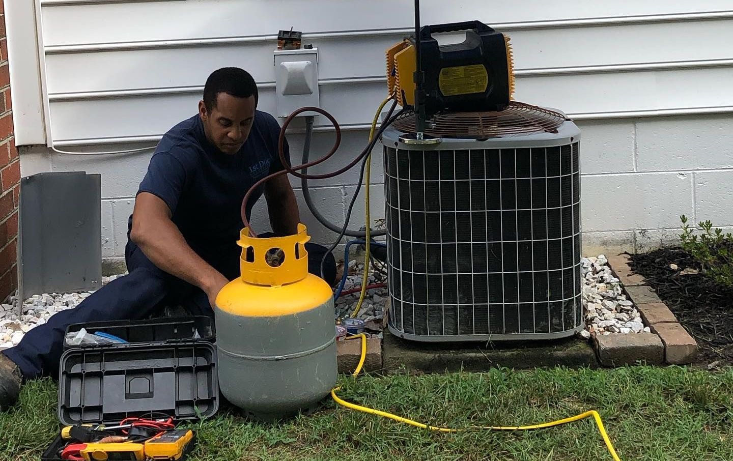 A large air conditioner is sitting outside of a brick building.