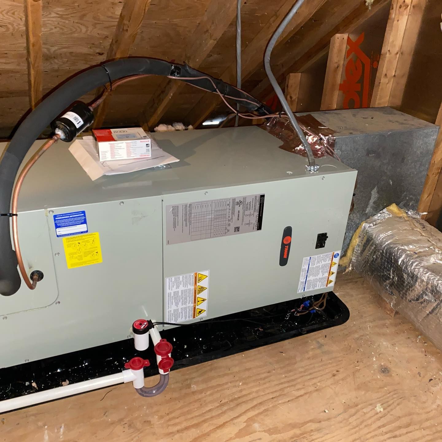 A box with a hose attached to it is sitting on a wooden floor.