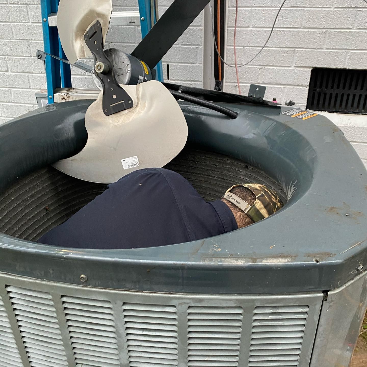 A man is laying inside of an air conditioner.