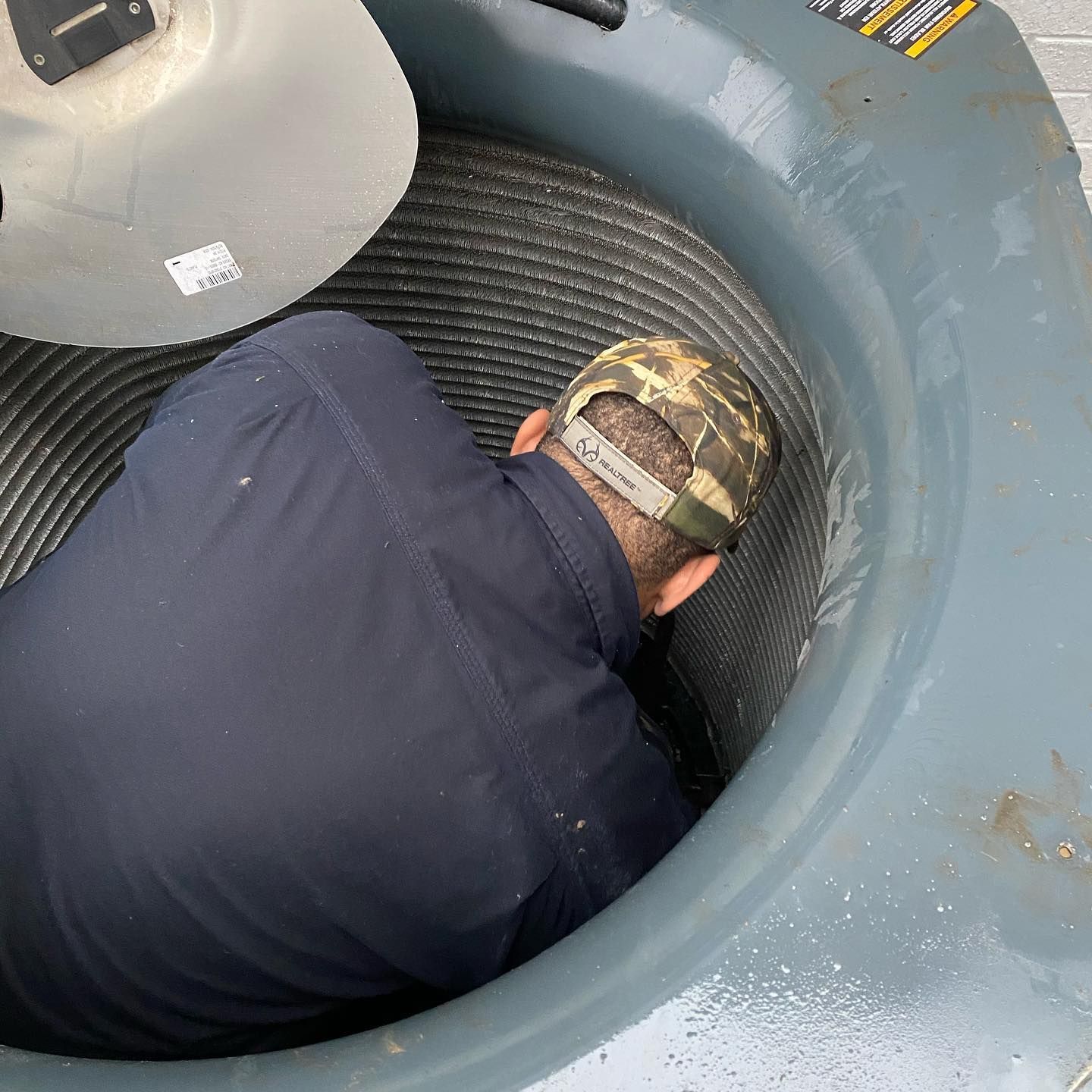 A man wearing a hat is laying in the middle of a machine.