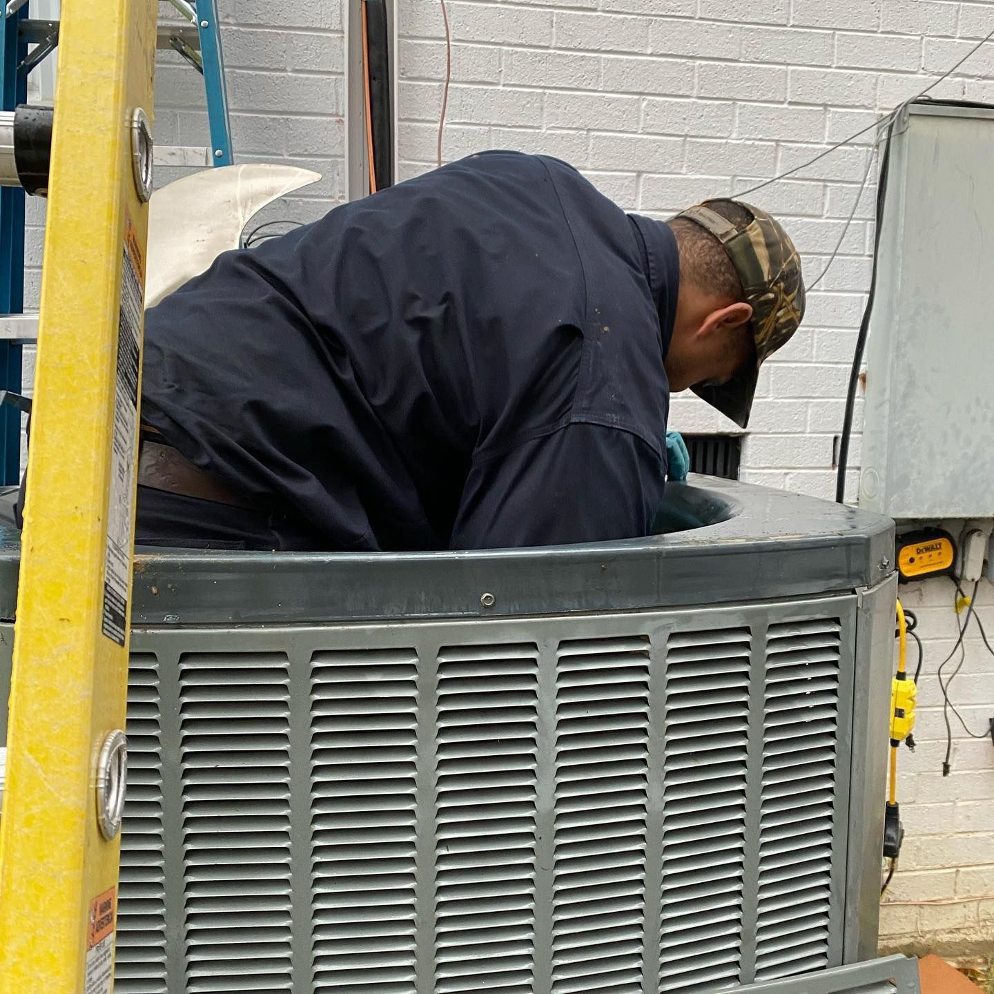 A man is working on an air conditioner outside of a building.