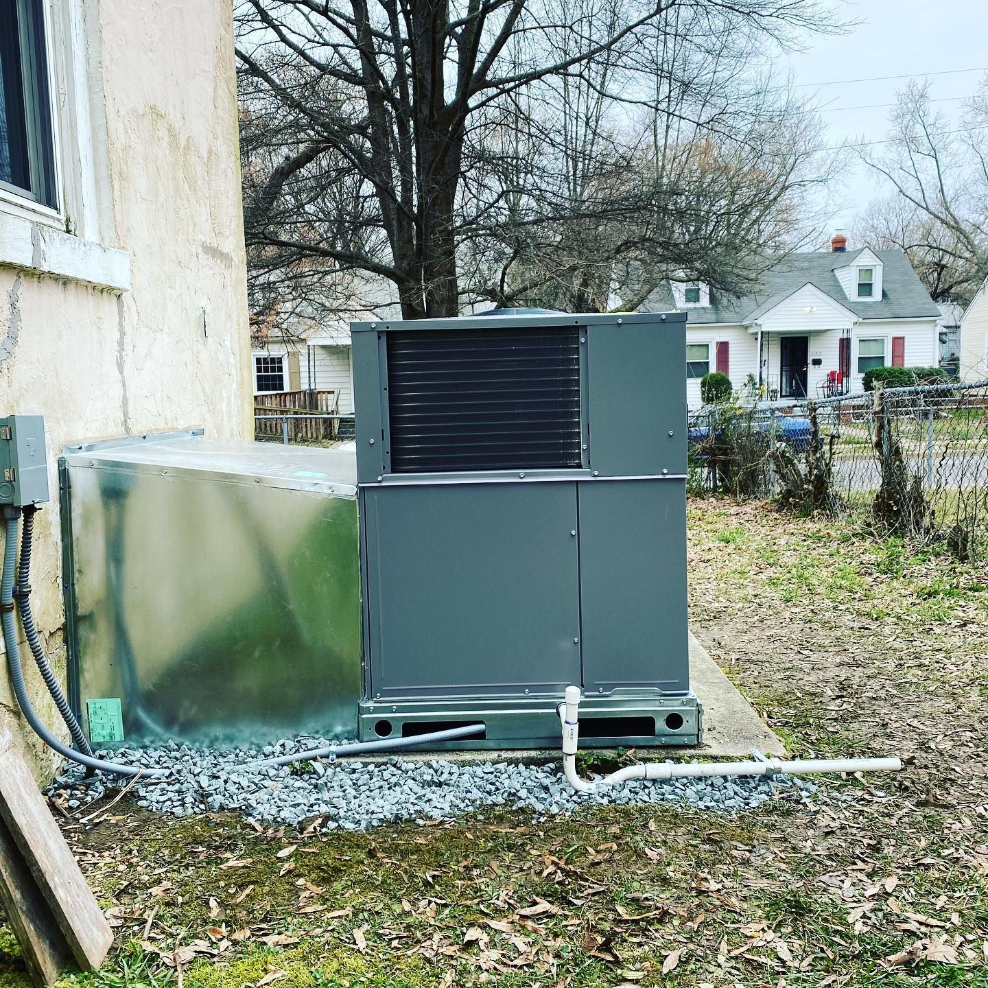 A large air conditioner is sitting on the side of a house.