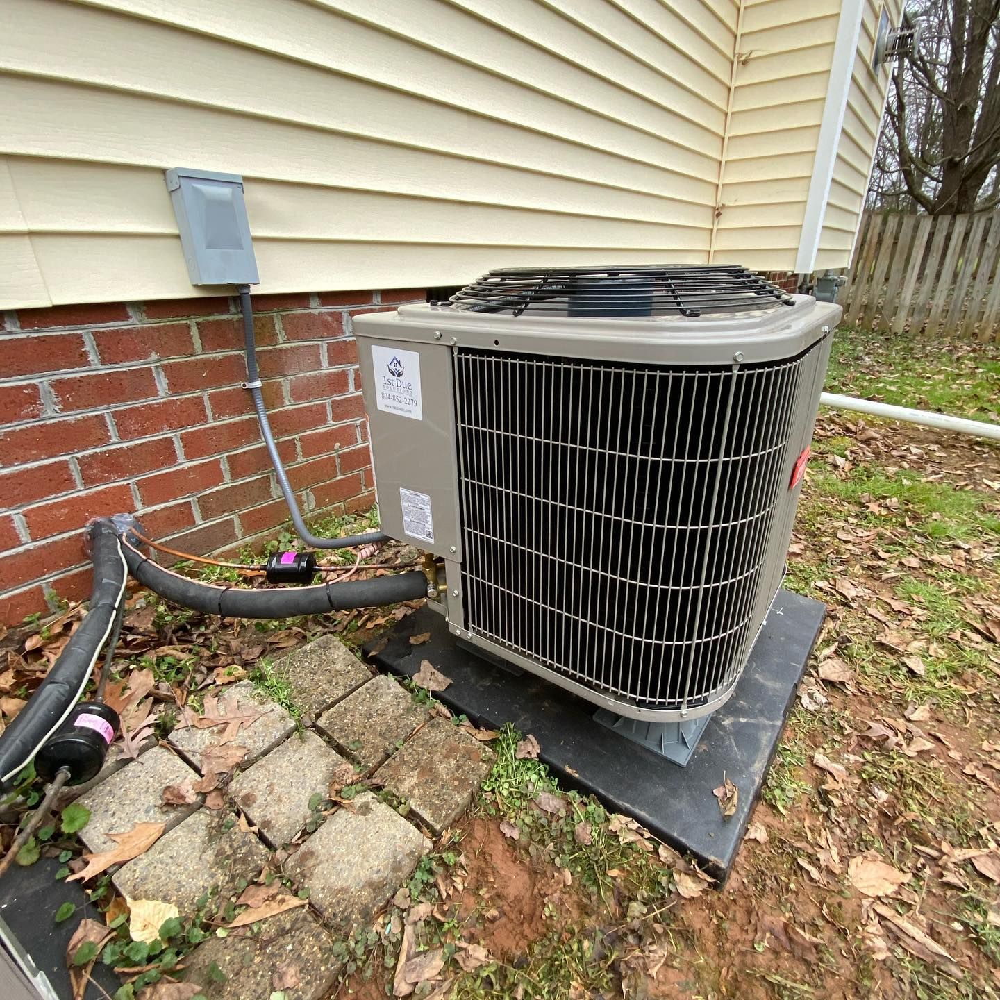 An air conditioner is sitting outside of a house next to a brick wall.