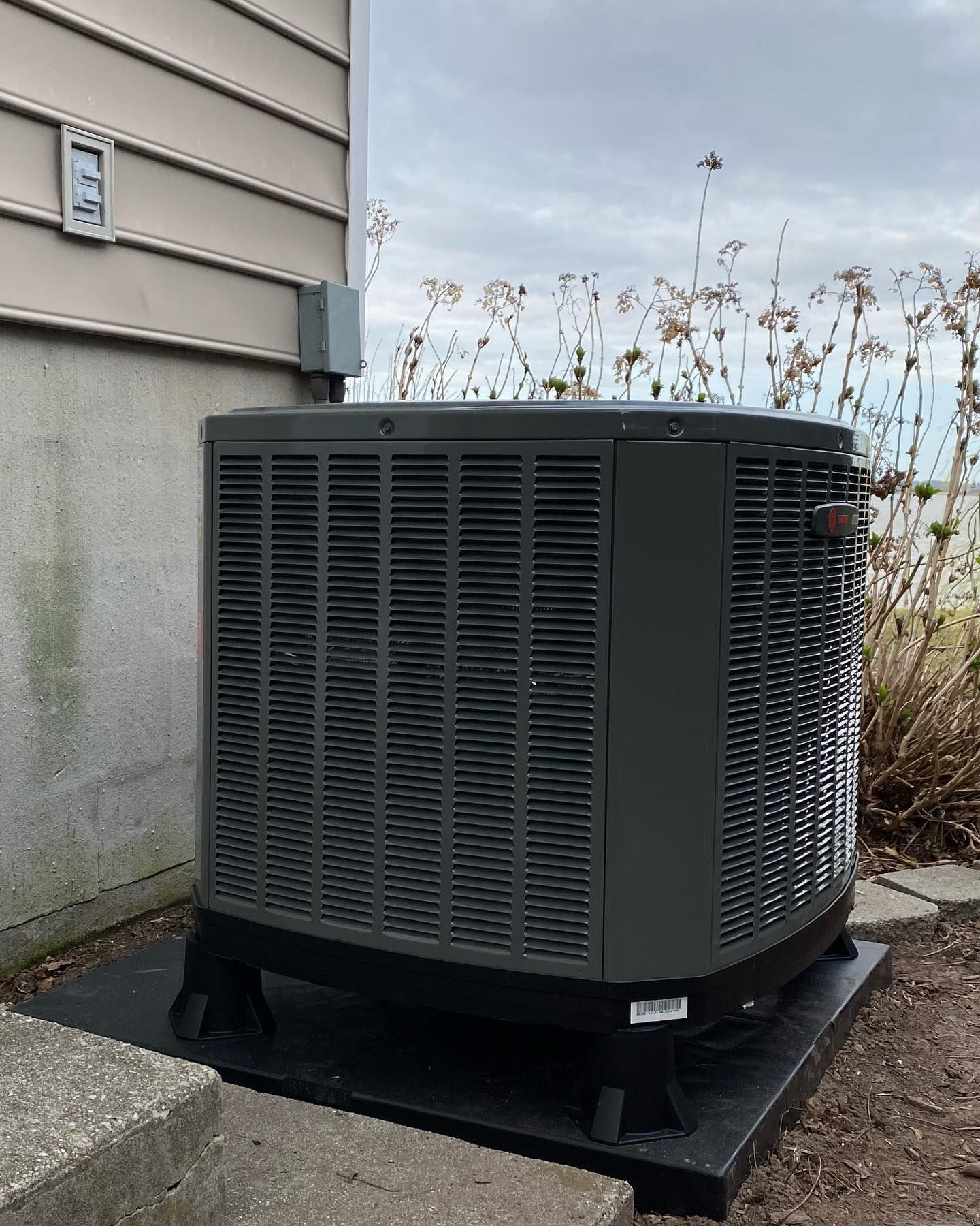 A large air conditioner is sitting outside of a house.