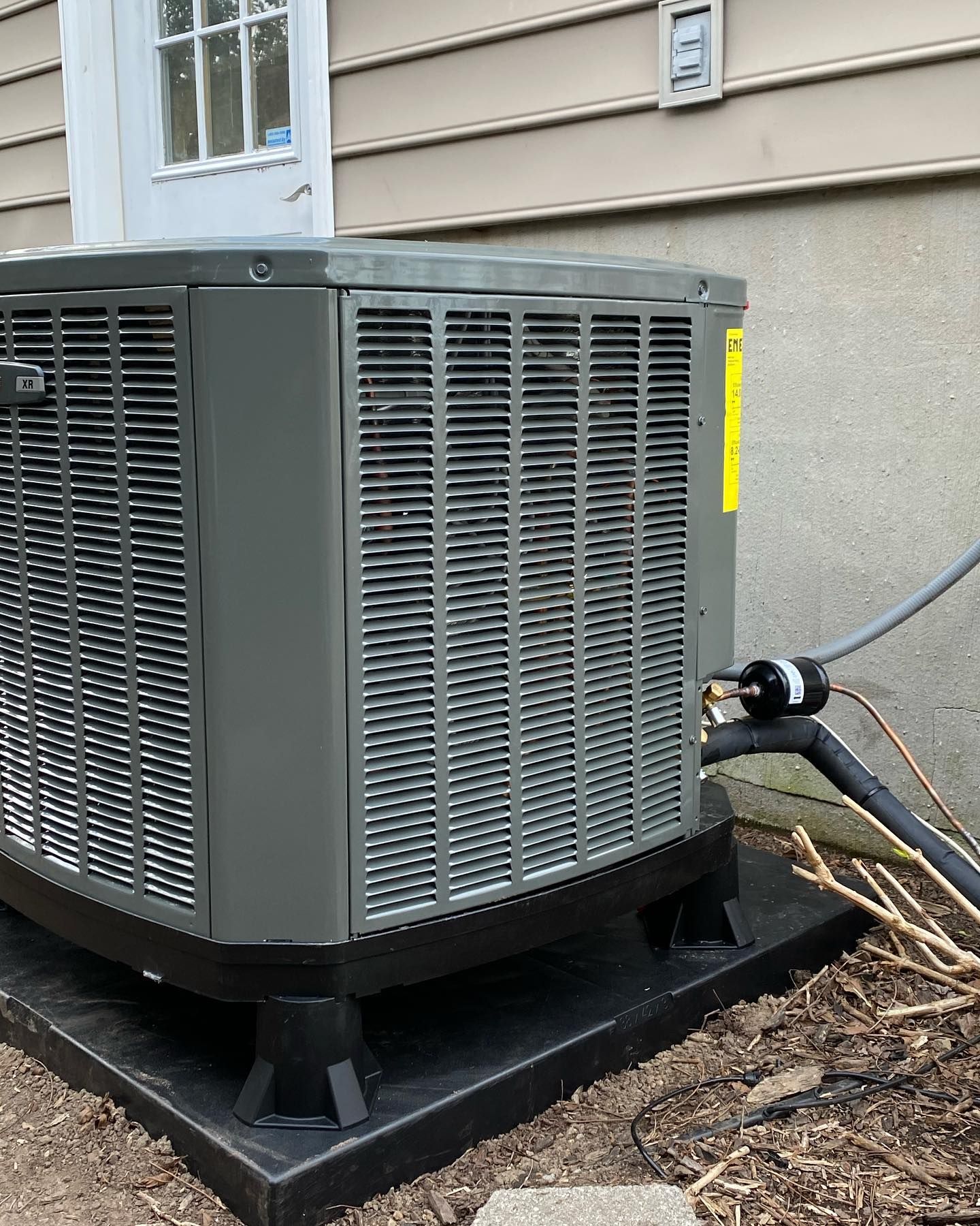 A large air conditioner is sitting outside of a house.