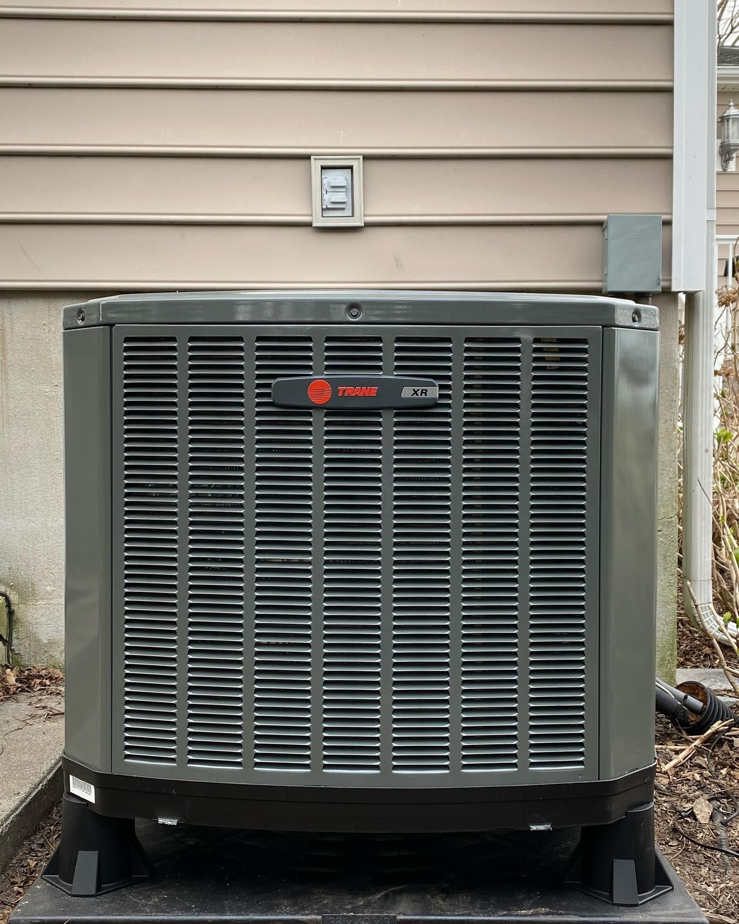 An air conditioner is sitting outside of a house.