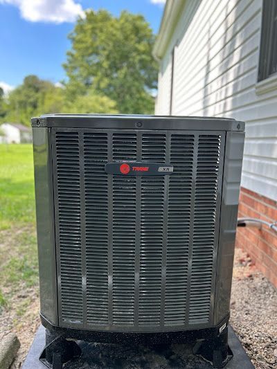 A large air conditioner is sitting outside of a house.
