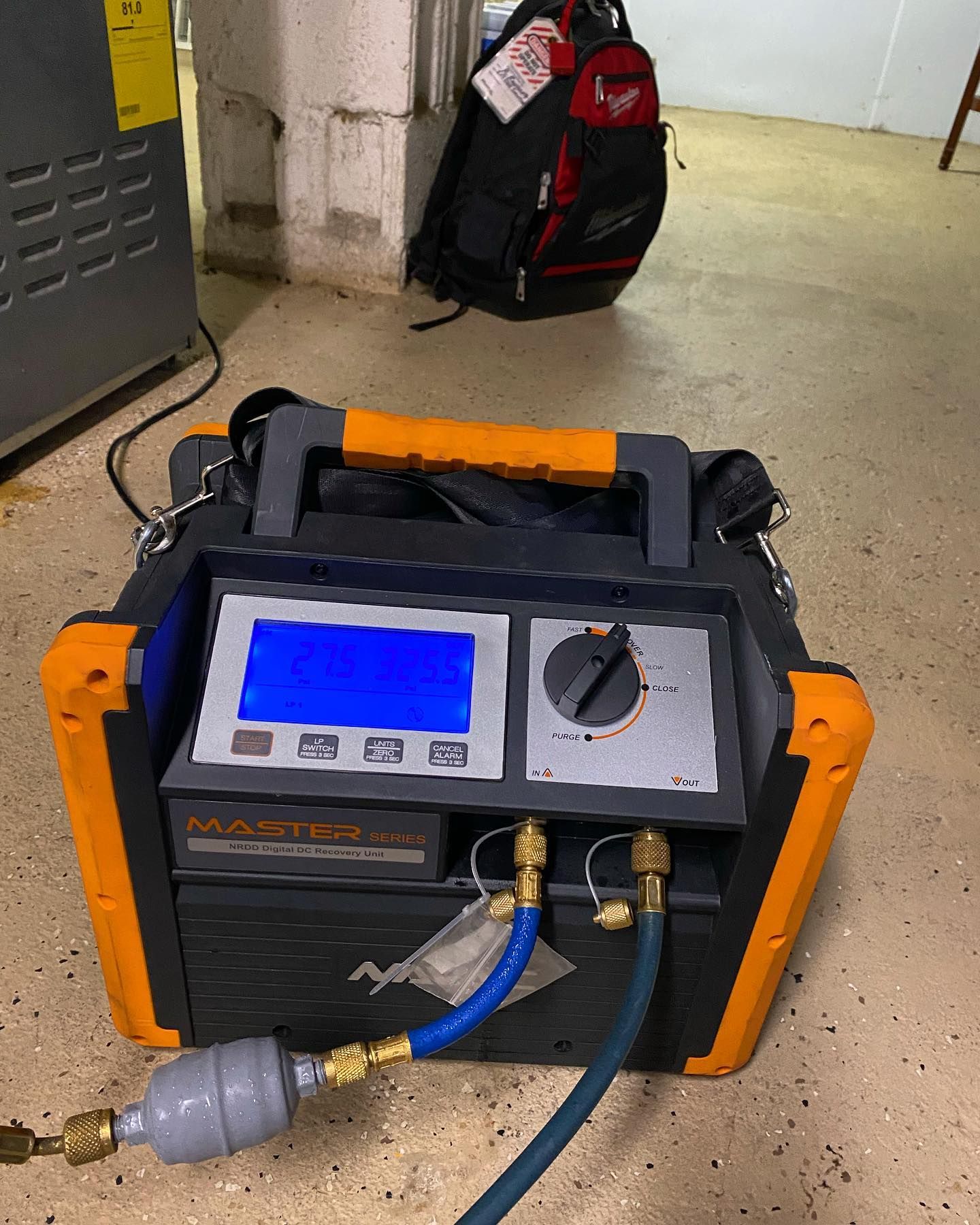 A machine is sitting on the floor next to a backpack.