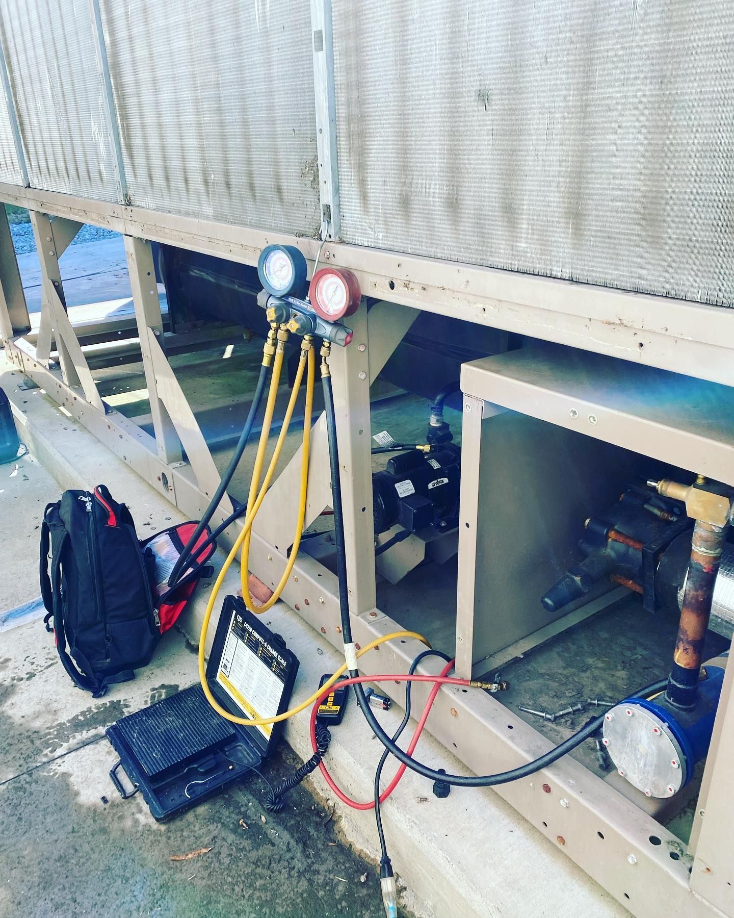 A bag of tools is sitting on the ground next to a machine.