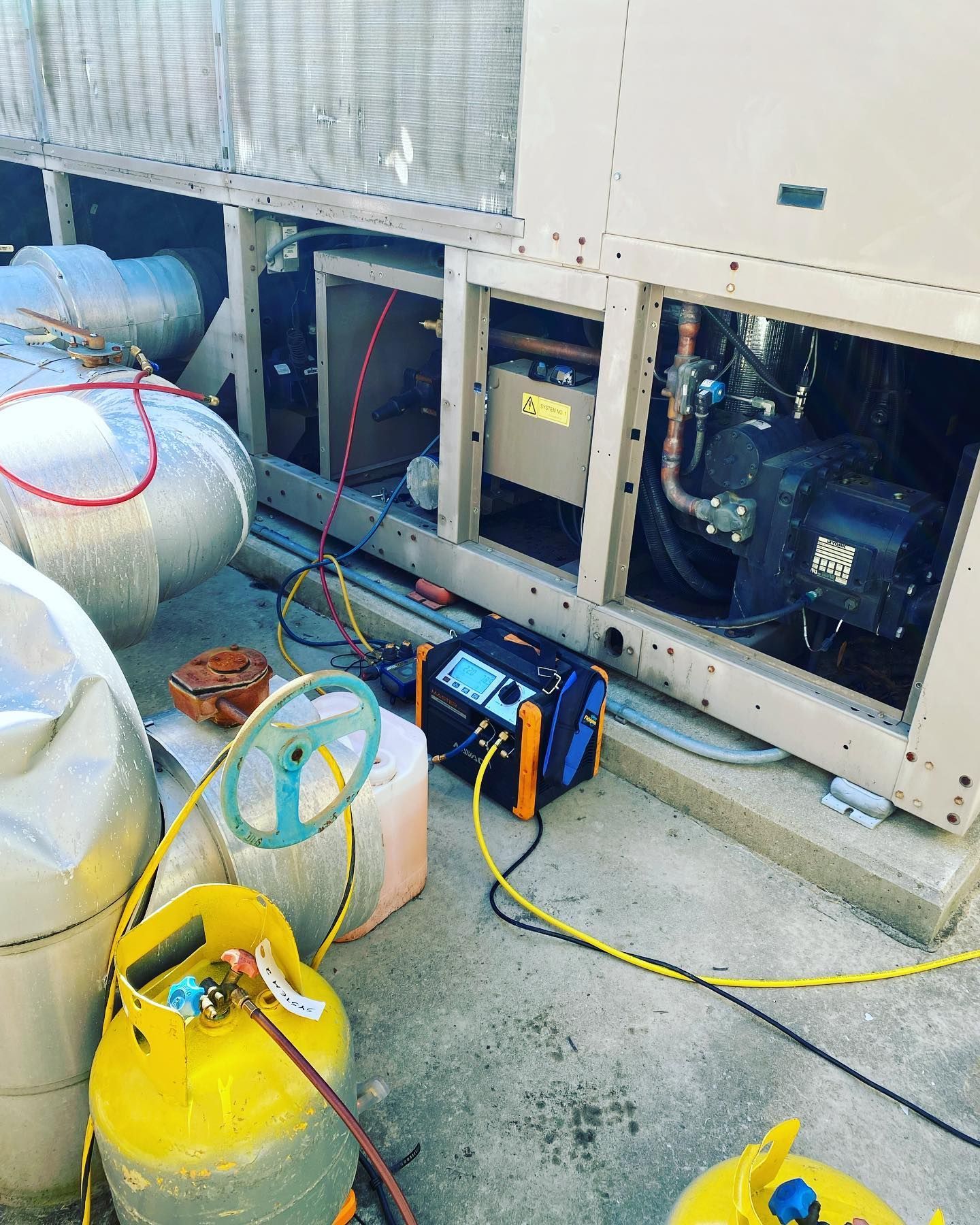 A propane tank is sitting on the ground next to a machine.