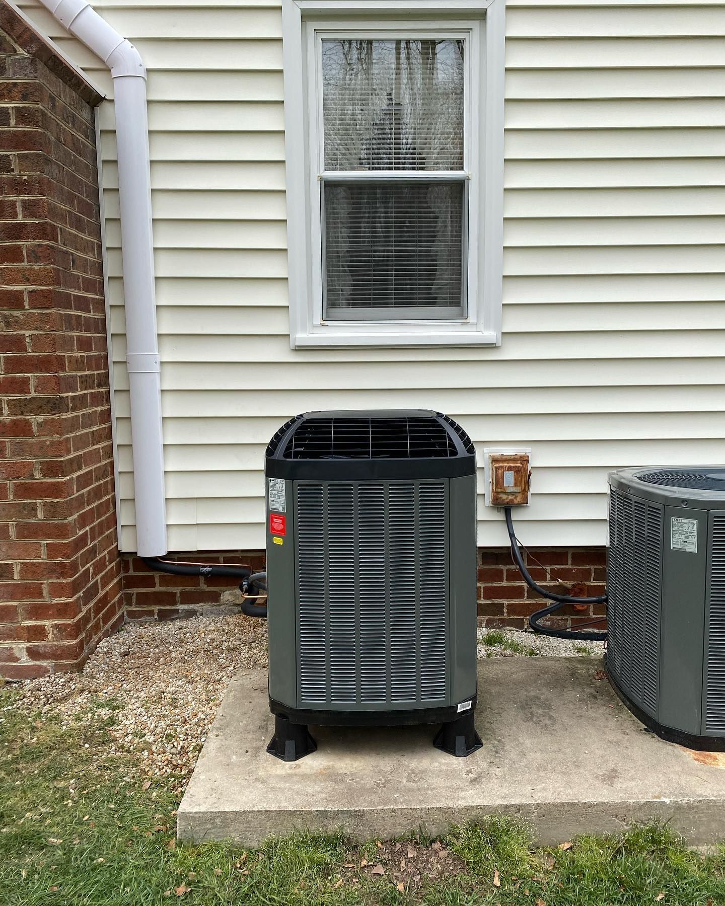 A couple of air conditioners are sitting outside of a house.
