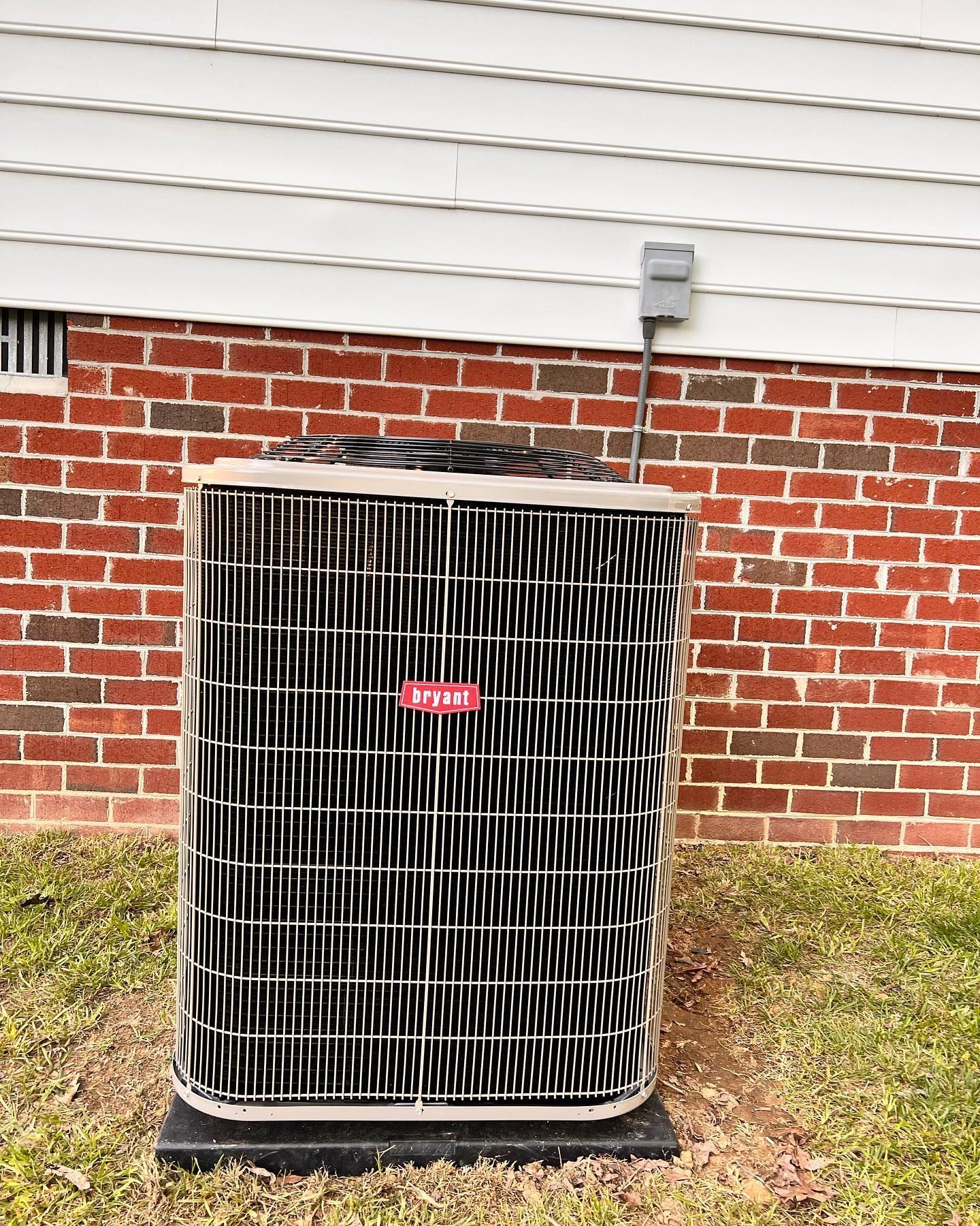 An air conditioner is sitting in front of a brick building.